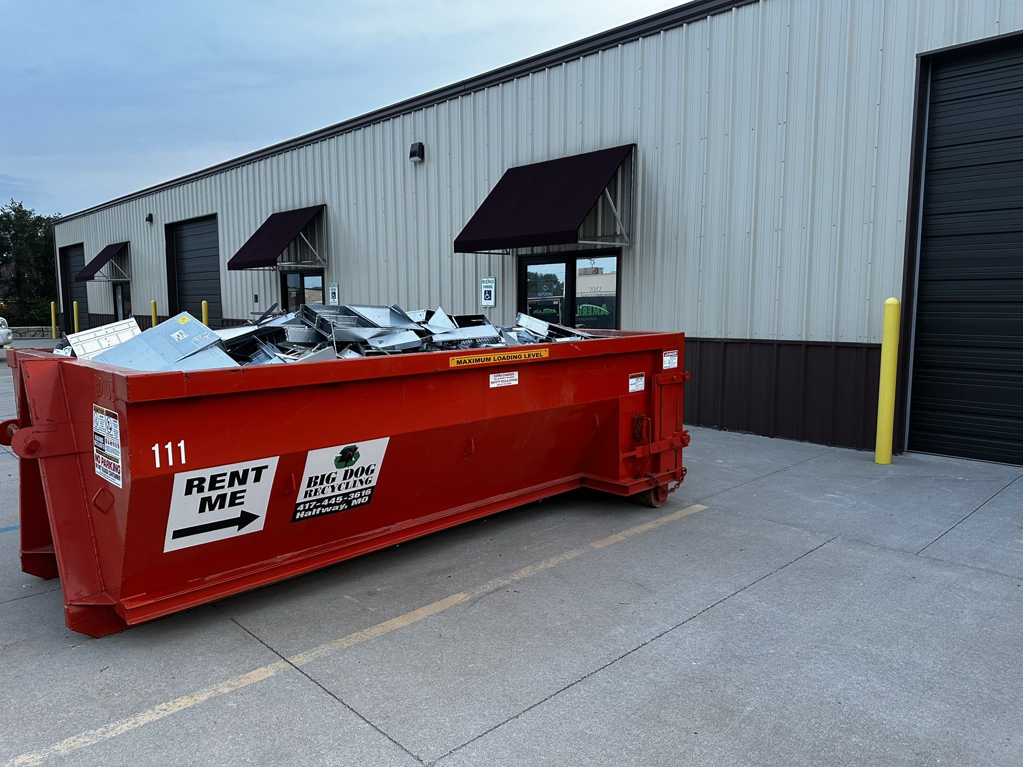 Large red recycling dumpster filled with electronics at an e-waste facility